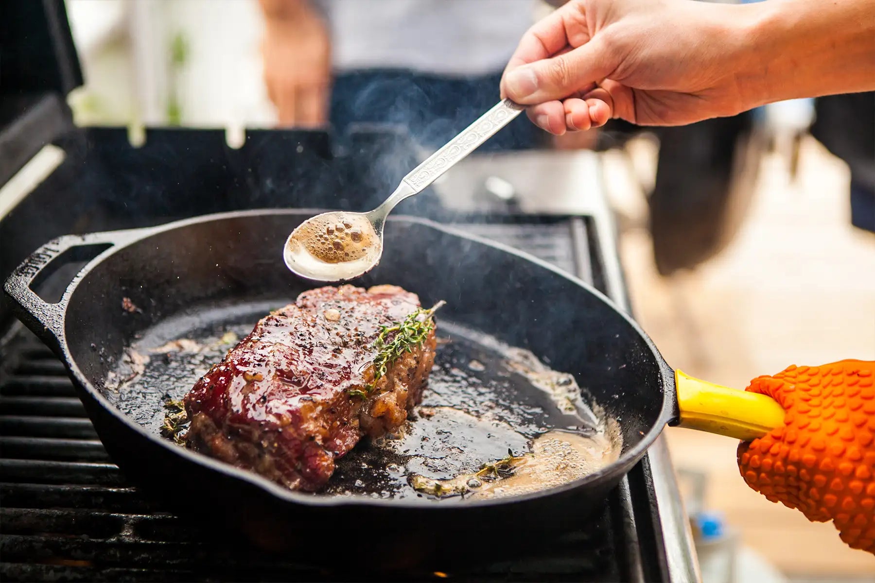 Halal Steak von Reinweide wird in einer Gusseisenpfanne gebraten und mit Bratenfett übergossen