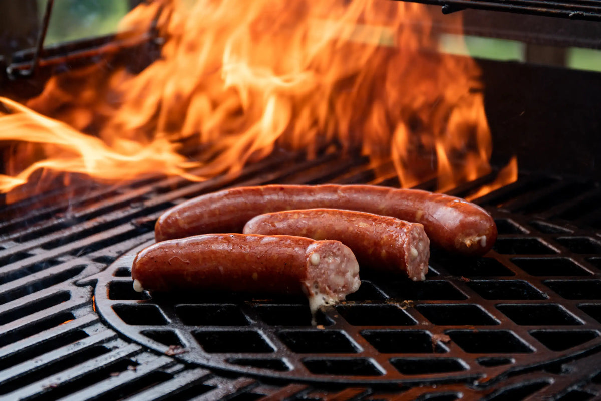 Käsekrainer mit austretendem Käse auf dem Grillrost